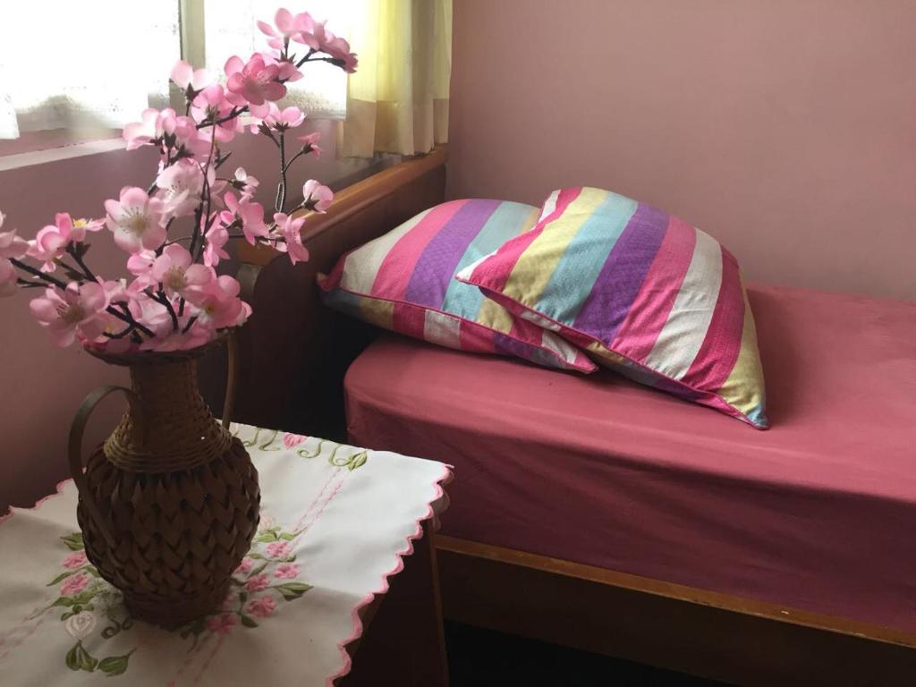 1 dormitorio con 1 cama con un jarrón de flores sobre una mesa en Astani Family Home en Bukittinggi