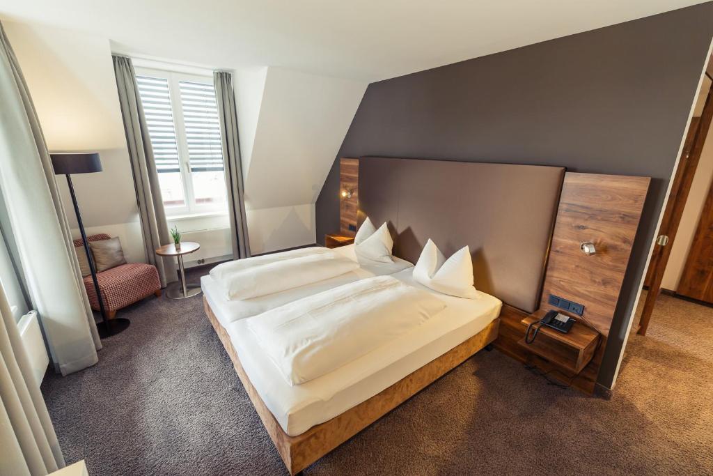 a bedroom with a large white bed in a room at Altstadthotel Kneitinger, Abensberg in Abensberg