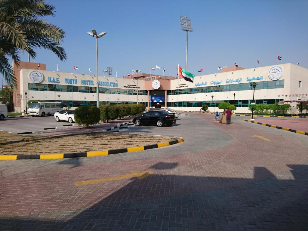 a parking lot in front of a large building at Dubai Youth Hotel in Dubai