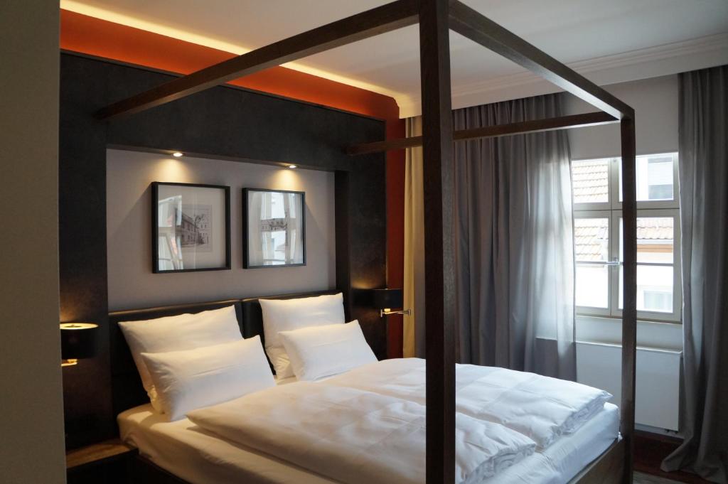 a bedroom with a canopy bed with white pillows at Ebracher Hof in Schweinfurt