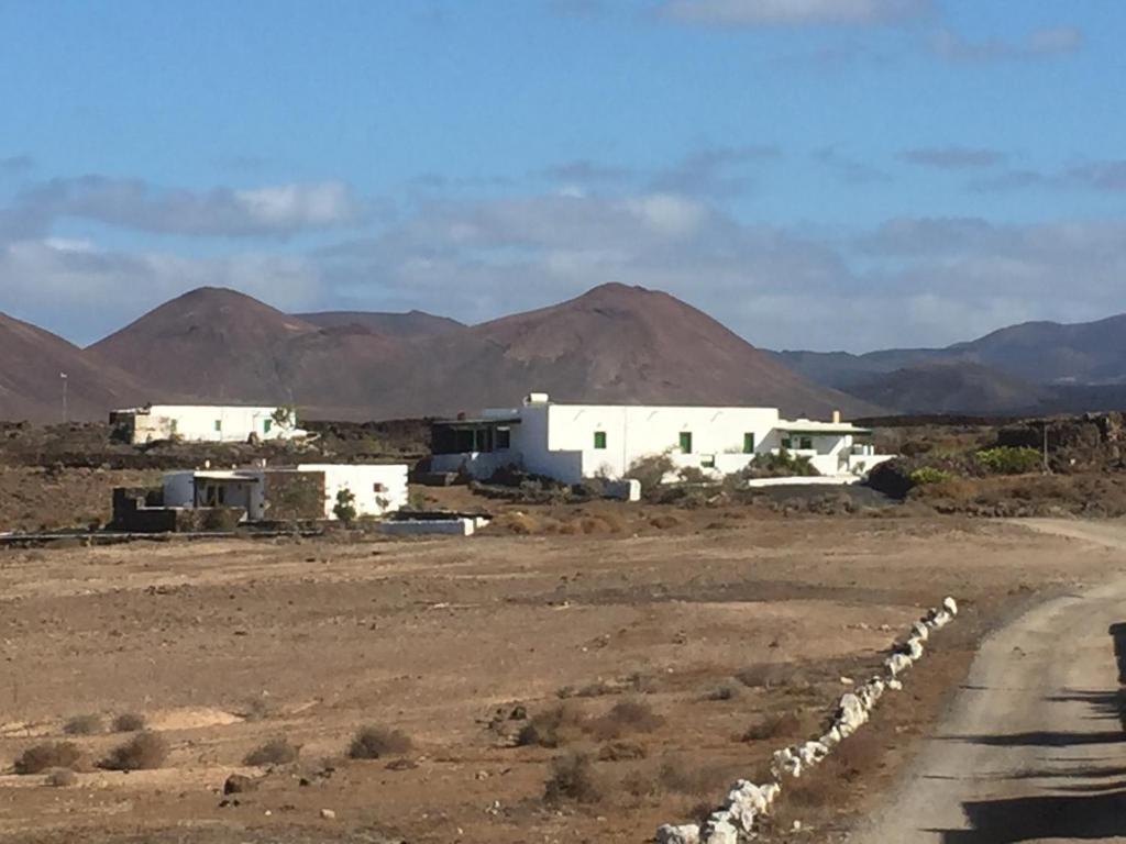 a group of white buildings in a desert with mountains at Finca La Hoya in Yaiza