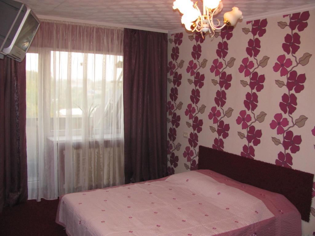 - une chambre avec un lit rose et une fenêtre dans l'établissement Bon Apart Avangard, à Mykolaïv