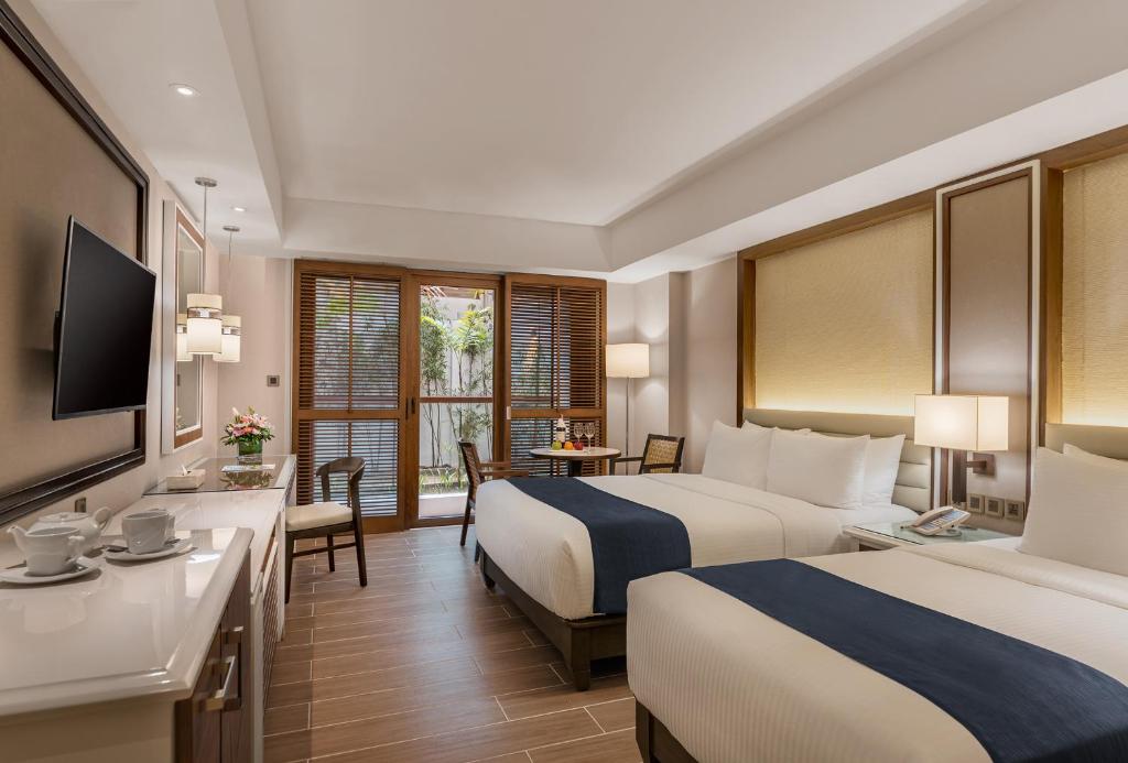 a hotel room with two beds and a desk at Henann Crystal Sands Resort in Boracay