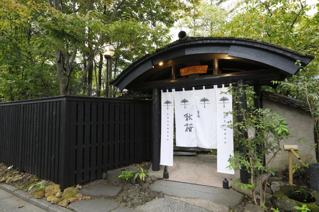 湯布院的住宿－湯布院草庵秋櫻日式旅館，黑色的大门,上面有标志