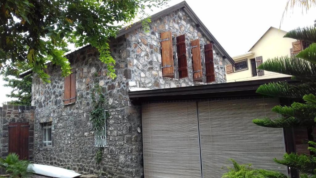 a stone house with a garage at La grange de G. in Grand Gaube