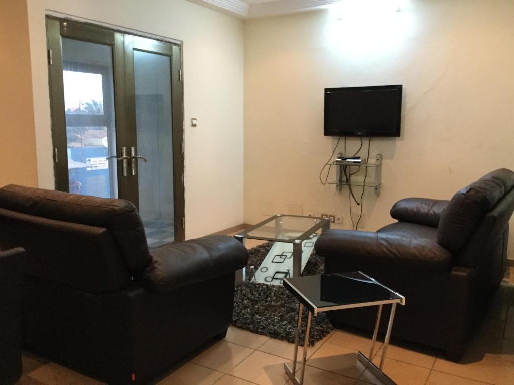 sala de estar con 2 sillas y TV en Julmarte en Lomé