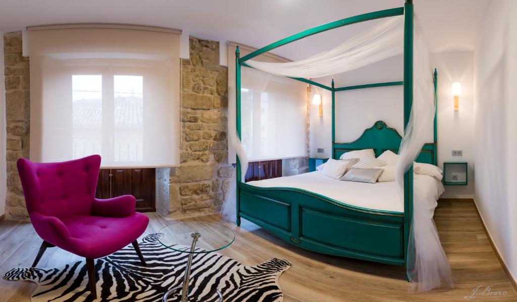 a bedroom with a green canopy bed and a red chair at La Casona de Alútiz & Bodega in Samaniego