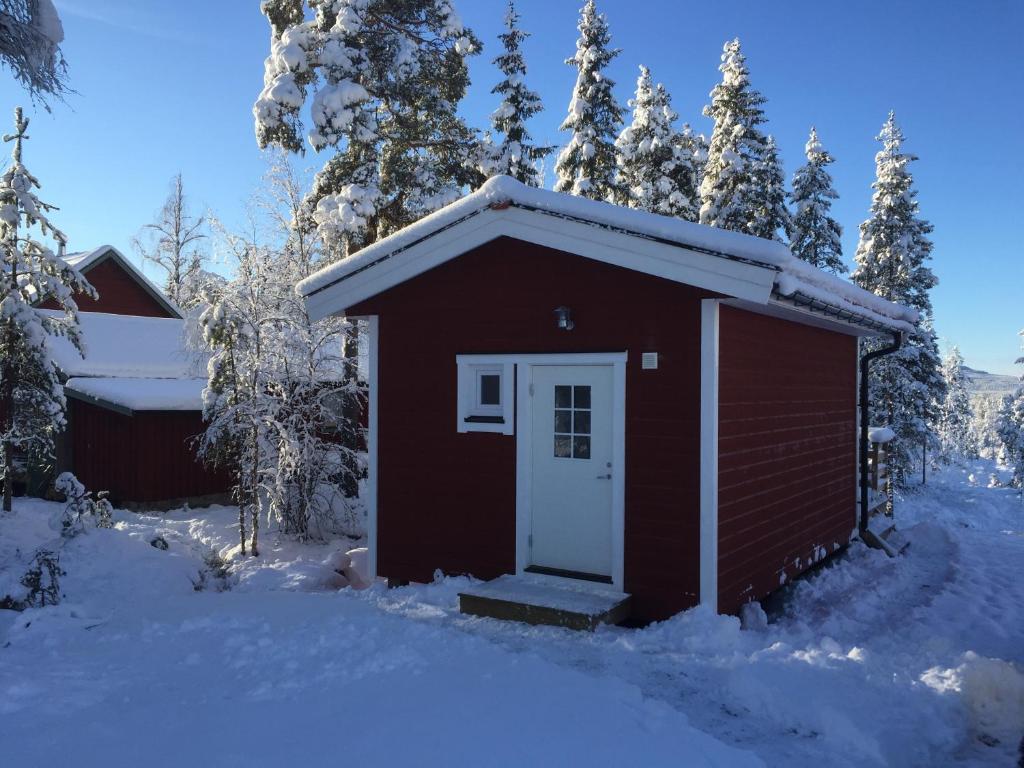 un pequeño cobertizo rojo con una puerta blanca en la nieve en Fjällstuga en Idre