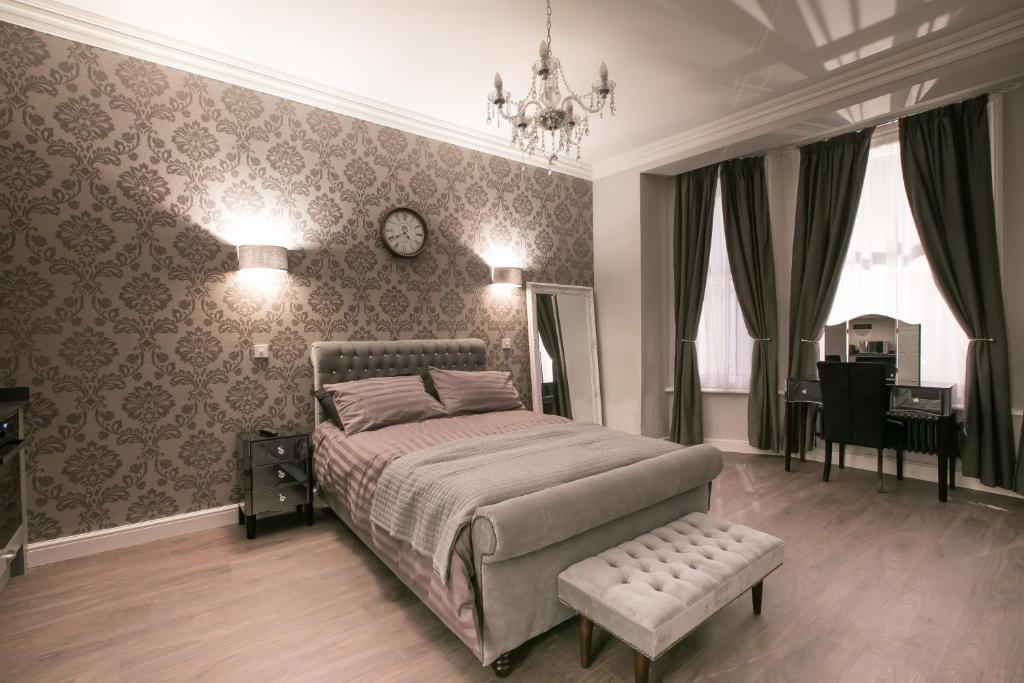 a bedroom with a bed and a chair and a clock at Apartments at Number 10 The Abbey in Norwich