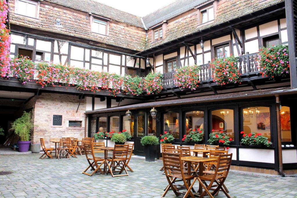 a courtyard of a building with chairs and flowers at Le Gouverneur Hotel in Obernai