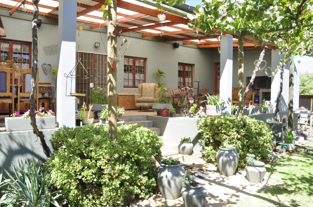 a patio with a bunch of plants and trees at Huisie Ommie Hoek in Uniondale