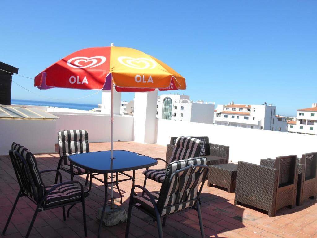 uma mesa e cadeiras debaixo de um guarda-sol num telhado em O Presidente em Portimão