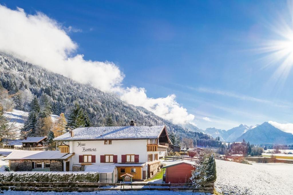 a house in the mountains with snow on the ground at "Haus Berktold" - Annehmlichkeiten von 4-Sterne Familien-und Wellnesshotel Viktoria können mitbenutzt werden in Oberstdorf