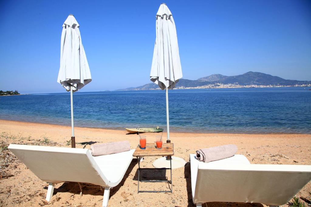 twee stoelen en een parasol op een strand bij Villas les Residences de Scaglione in Porticcio