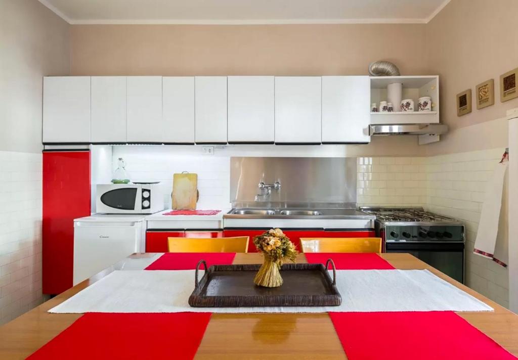 アベトーネにあるAppartamento Il Pungitopoのキッチン(赤と白のキャビネット、テーブル付)