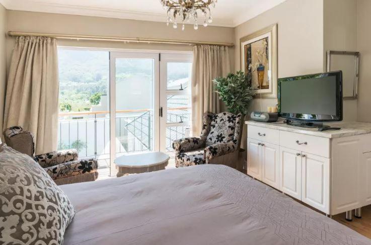 a bedroom with a bed with a television and a balcony at Anna's Place in Cape Town