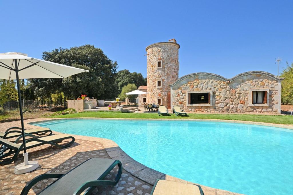 a swimming pool in front of a stone building at Villa Molinot in Búger