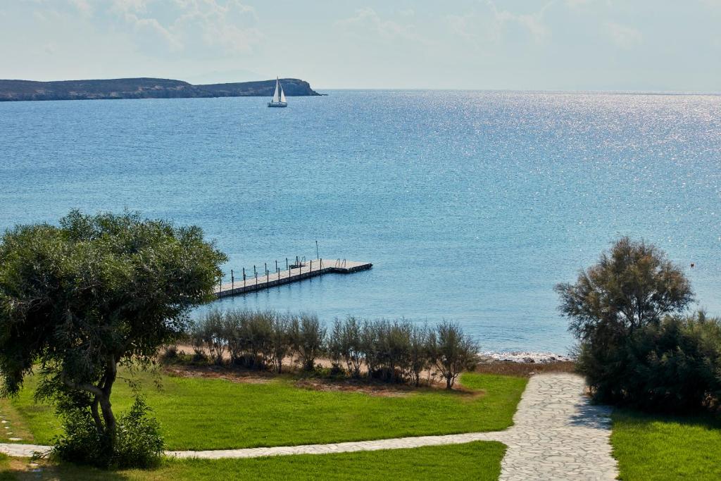 Poseidon of Paros Hotel & Spa في كريس أكتي: قارب شراعي في الماء بجانب رصيف