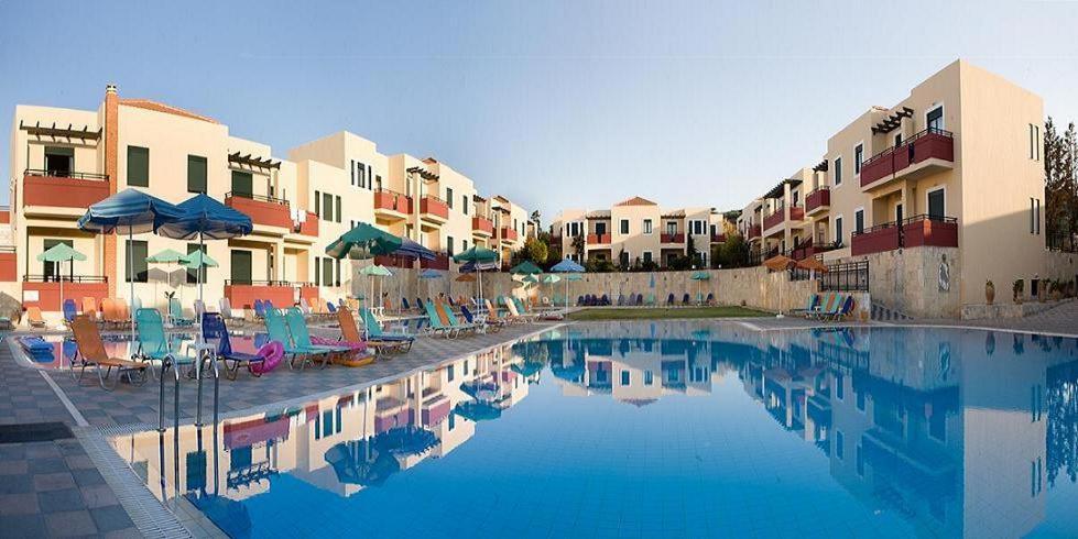 a swimming pool with chairs and umbrellas next to buildings at Kambos Village in Agia Marina Nea Kydonias