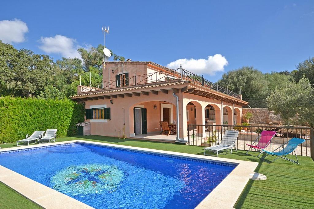 a villa with a swimming pool in front of a house at Villa Victori in Sineu