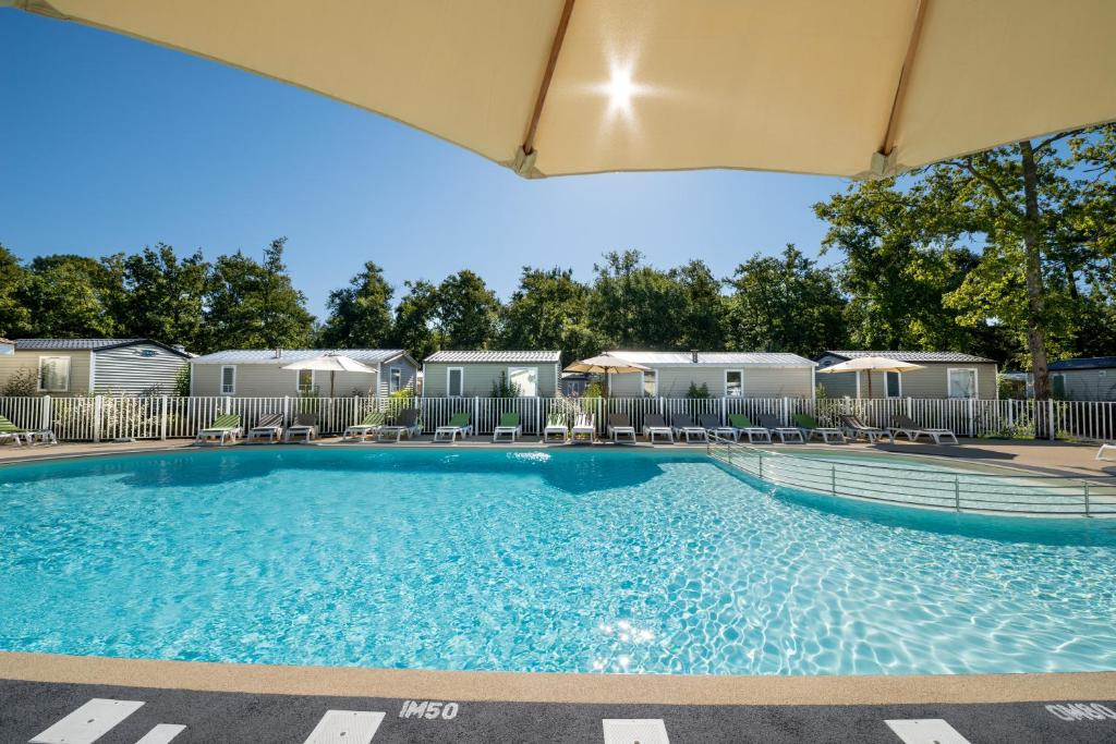 - une piscine dans un complexe avec des chaises et des tentes dans l&#39;établissement Camping Les Chèvrefeuilles, à Royan