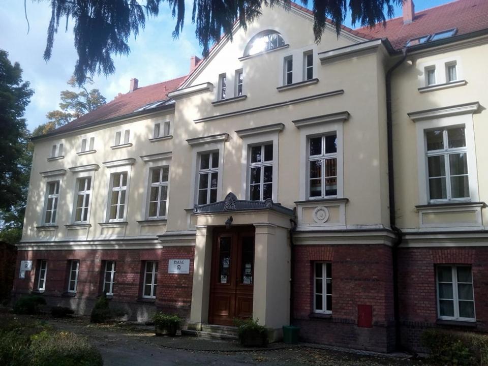 a large white building with a red brick at Stado Ogierów Sieraków in Sieraków