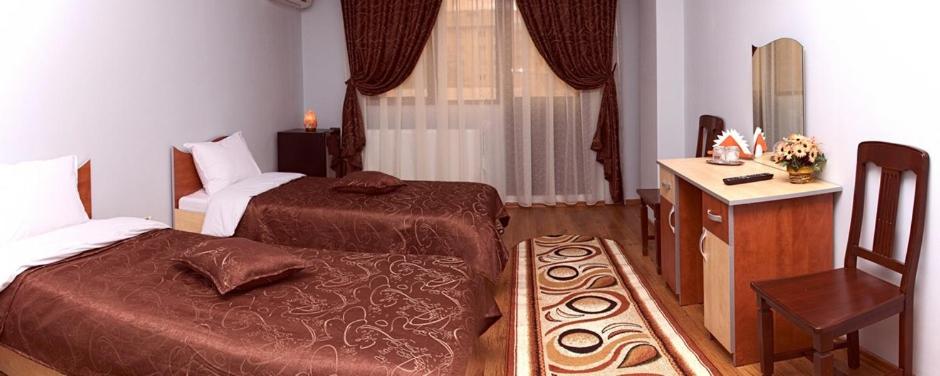 a bedroom with two beds and a desk and a chair at Hotel Corneliuss in Galaţi