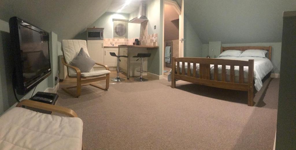 1 dormitorio con 1 cama, TV y silla en Somersall Park Studio en Chesterfield
