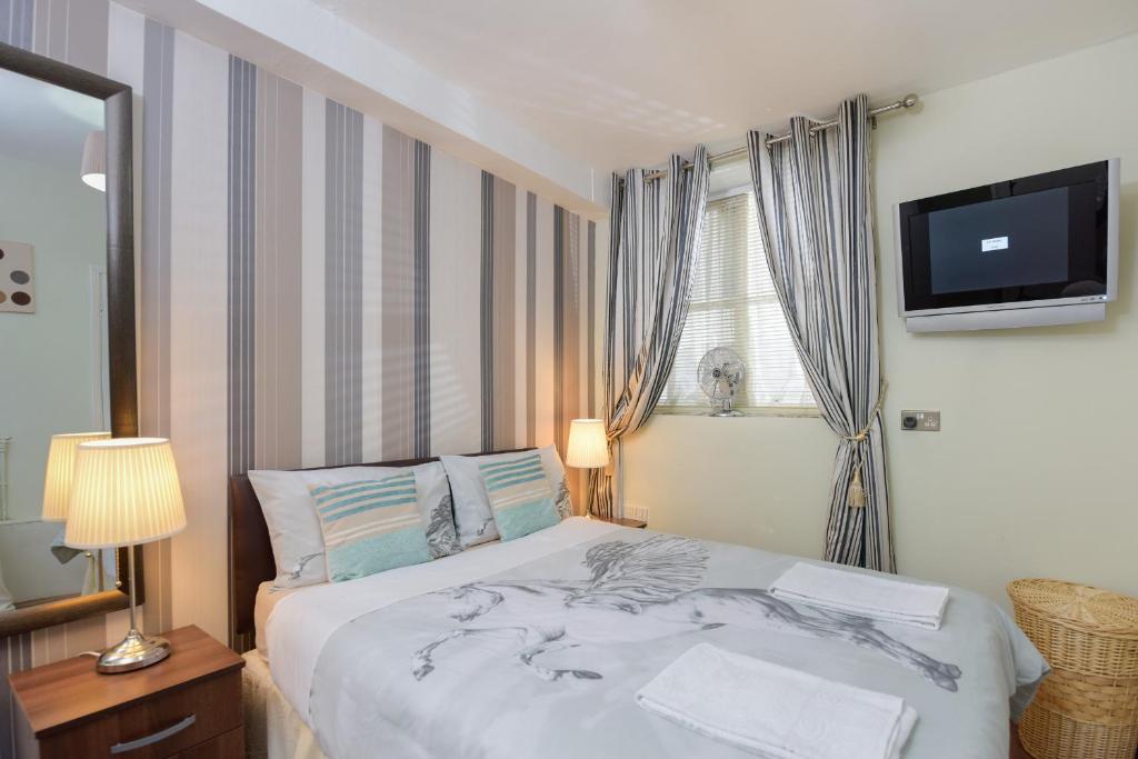 een slaapkamer met een groot bed en een televisie aan de muur bij Gloucester Gardens in Londen