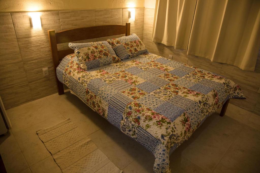 a bedroom with a bed with a quilt and pillows at Pousada da Guarda in Guarda do Embaú