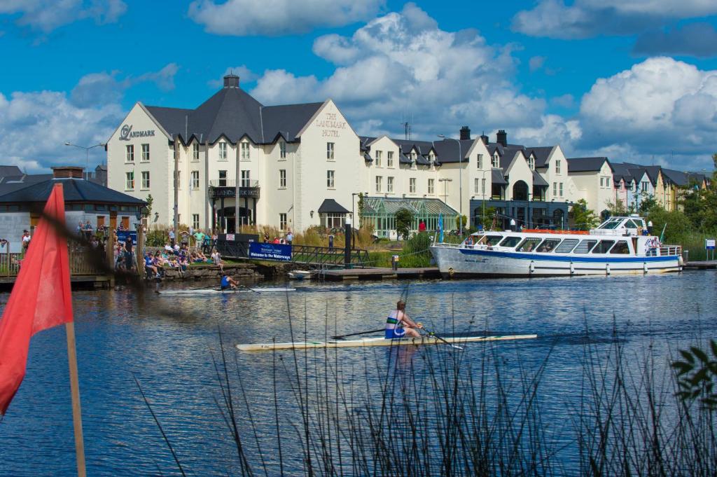 una persona che rema su una barca in acqua di fronte agli edifici di The Landmark Hotel a Carrick on Shannon