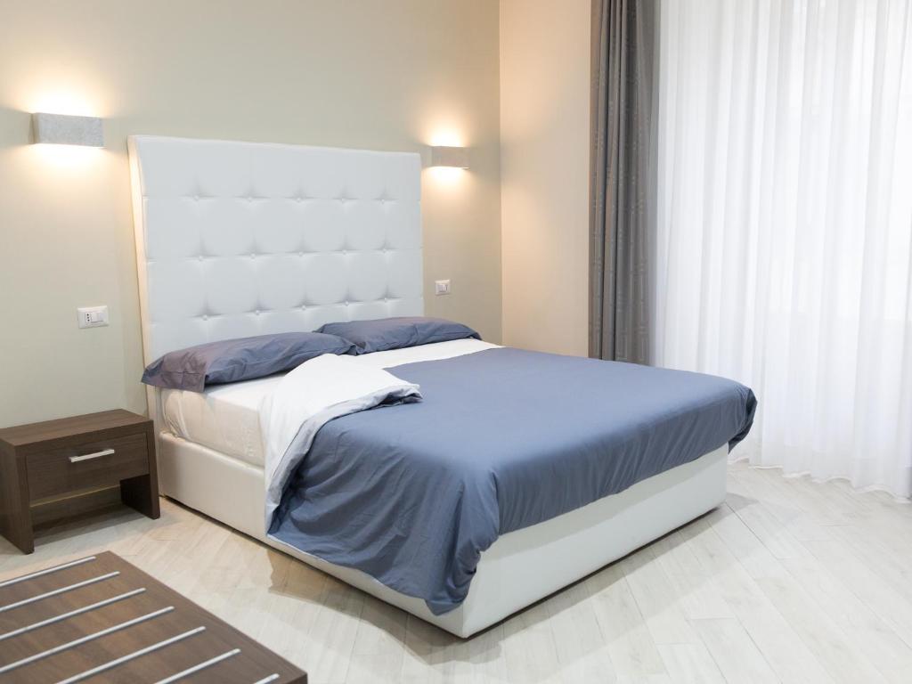 a bedroom with a large white bed with blue sheets at Venustas Roma Hotel in Rome