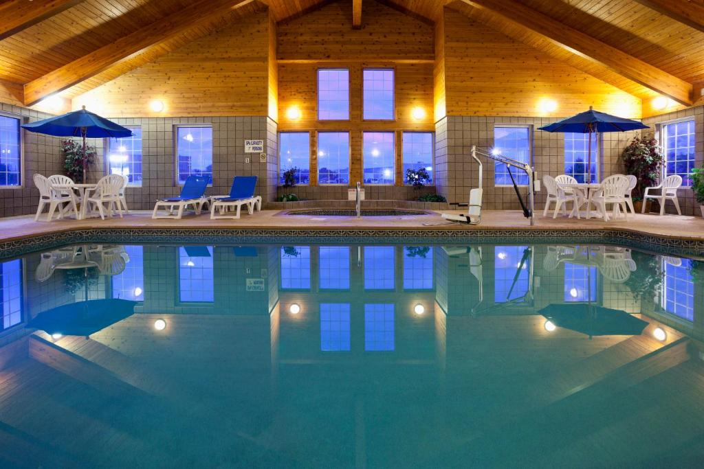a swimming pool with chairs and umbrellas in a building at Paynesville Inn & Suites in Paynesville