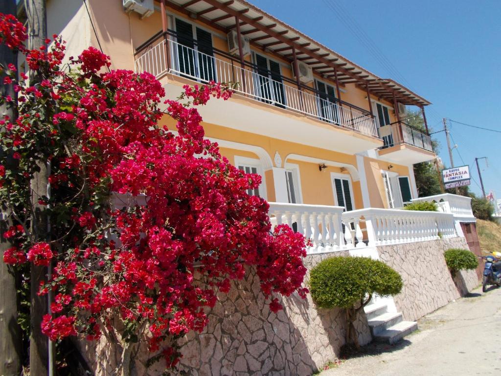 un edificio con flores rojas a un lado. en Kavos Fantasia Complex, en Kavos