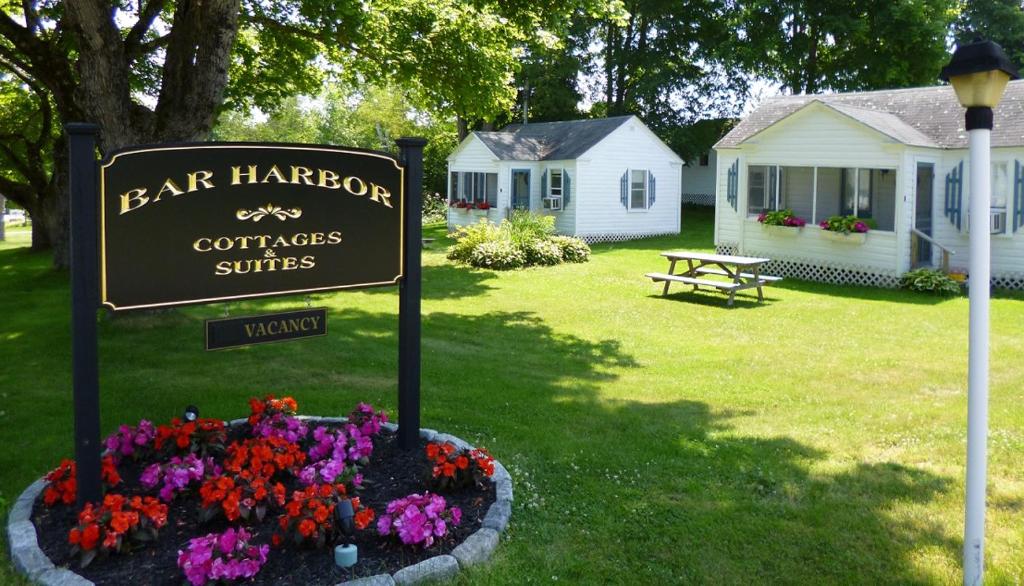 ein Schild in einem Blumenbett vor einem Haus in der Unterkunft Bar Harbor Cottages & Suites in Bar Harbor