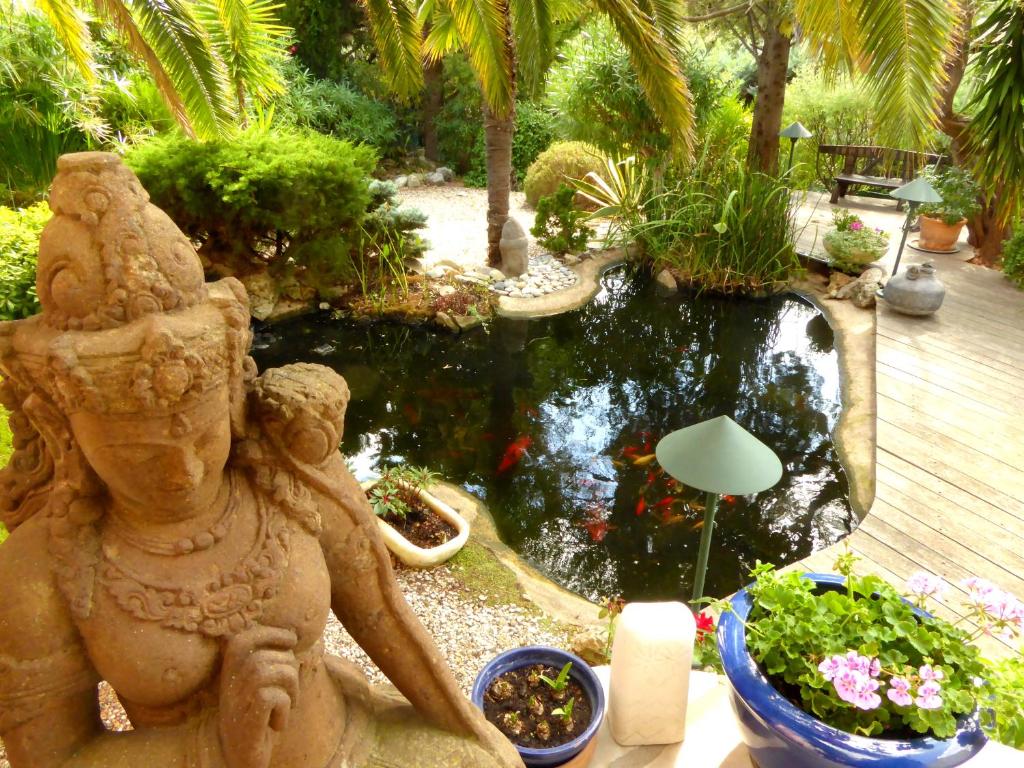 un jardín con un estanque koi y una estatua en Babou, en Mandelieu-la-Napoule