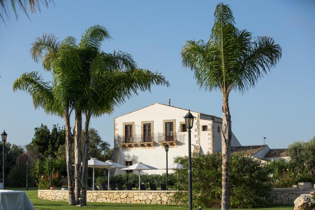 a white house with palm trees in front of it at Casal Sikelio in Cassibile