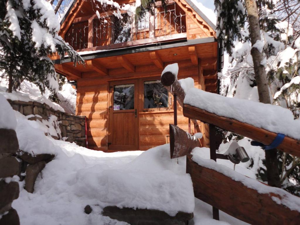 uma cabana de madeira na floresta com neve na cerca em Domki Mroz em Zakopane