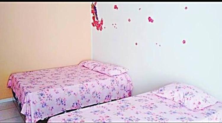 two beds in a bedroom with pink sheets at Pousada CPA in Cuiabá