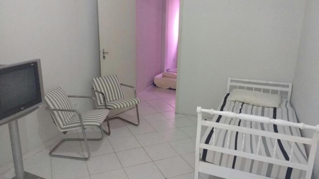 een woonkamer met 2 stoelen, een tafel en een tv bij Apartamento Praia da Costa in Vila Velha