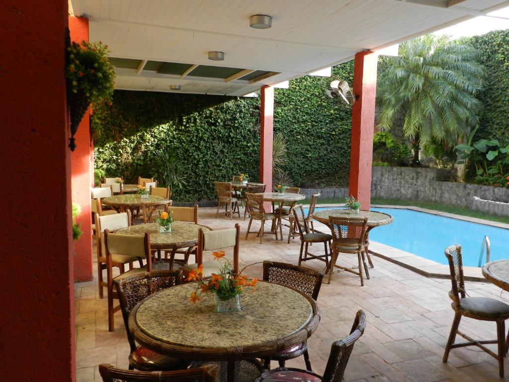 a patio with tables and chairs next to a pool at Eldorado Inn in Feira de Santana