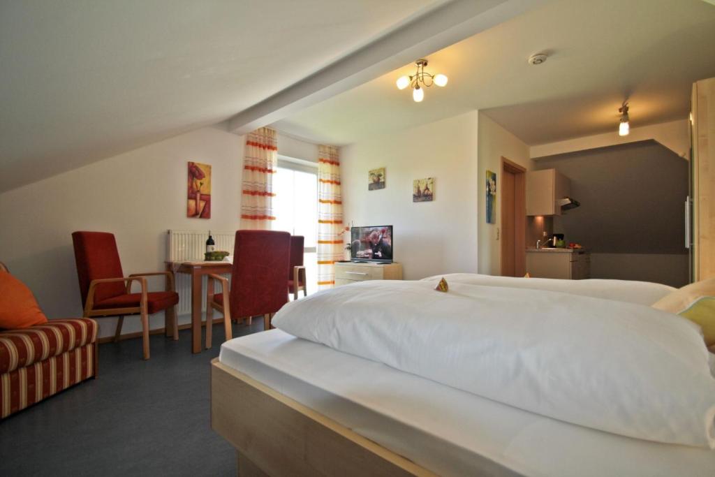 a bedroom with a white bed and a table and chairs at Ferienhof Rieger in Rotthalmünster