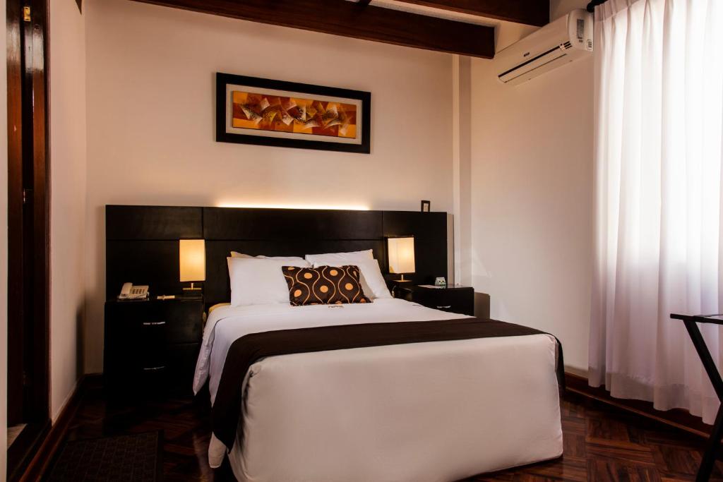 a bedroom with a large white bed with a black headboard at Hotel Ferre De Ville in Lima