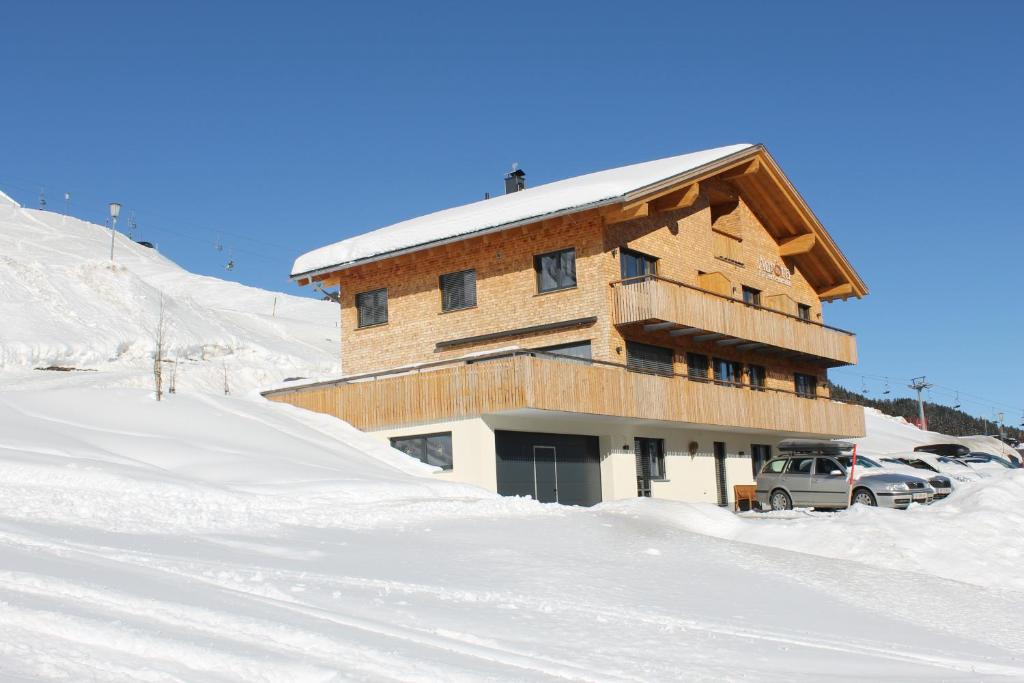 un edificio en la nieve con coches aparcados en él en Appartements Aurora, en Damüls