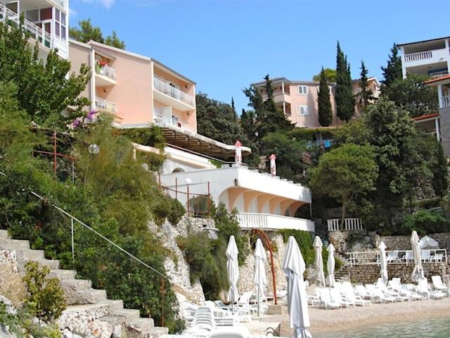 - un groupe de chaises longues et de parasols sur une plage dans l'établissement Rooms Tepli Bok, à Primošten