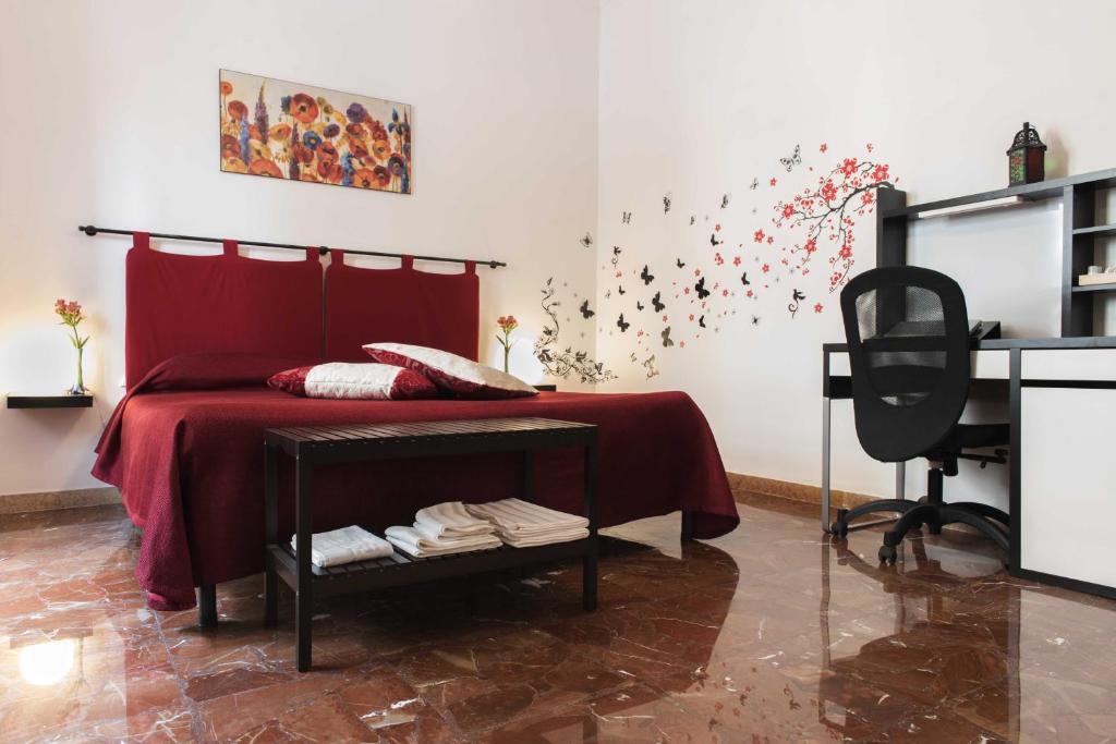 a bedroom with a bed with red sheets and a desk at Michelangelo Apartment in Civitavecchia