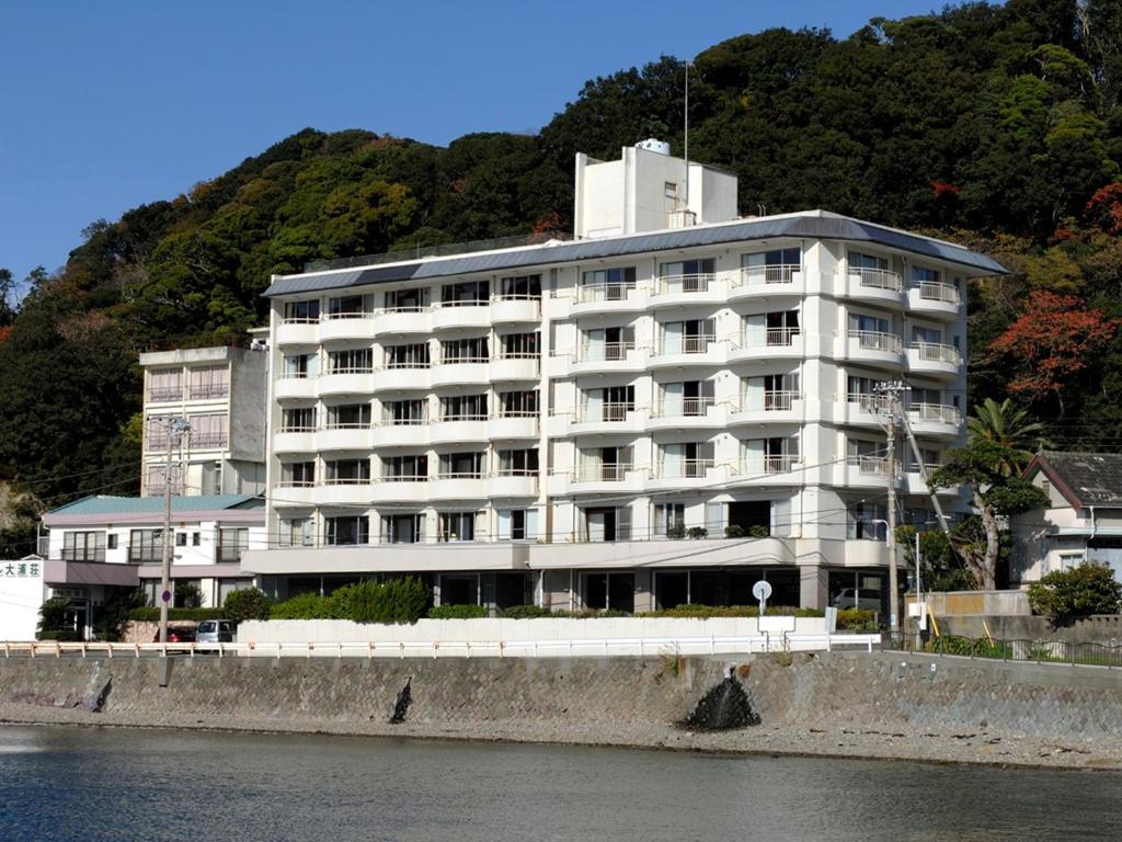 a large white building next to a body of water at Shimoda Kaihin Hotel in Shimoda