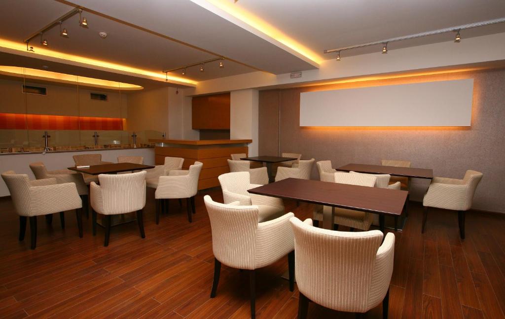 a restaurant with tables and white chairs and a screen at Hotel Flisvos in Kalamata