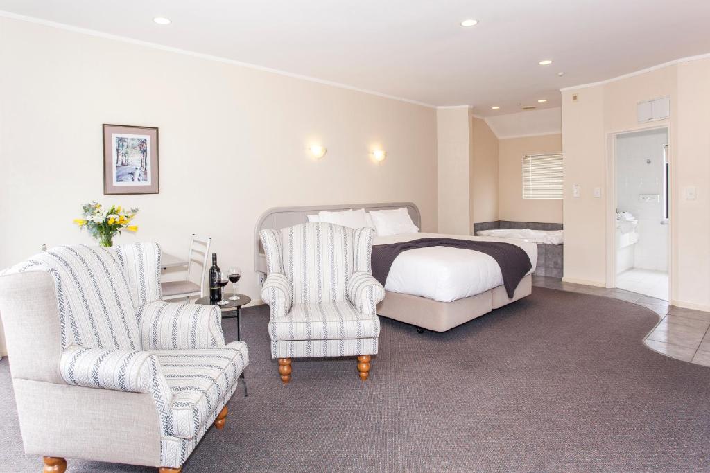 a bedroom with a bed and two chairs at Te Mata Lodge in Havelock North