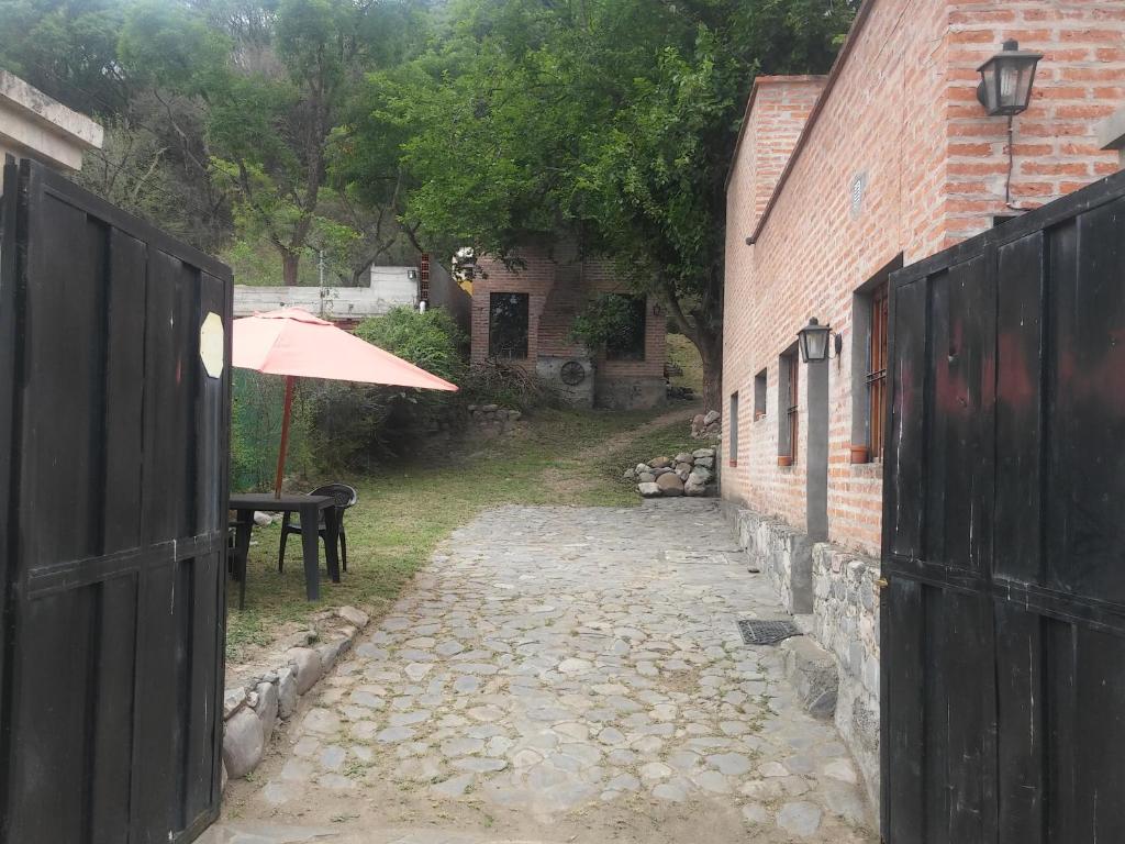 an alley with an umbrella next to a brick building at Cabaña San Pablo in San Salvador de Jujuy